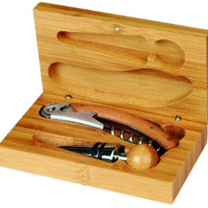 May include: A bamboo wine opener set in a wooden box. The set includes a corkscrew, a bottle stopper, and a foil cutter. The box is rectangular with a hinged lid and a natural wood finish. The corkscrew has a wooden handle and a stainless steel opener.