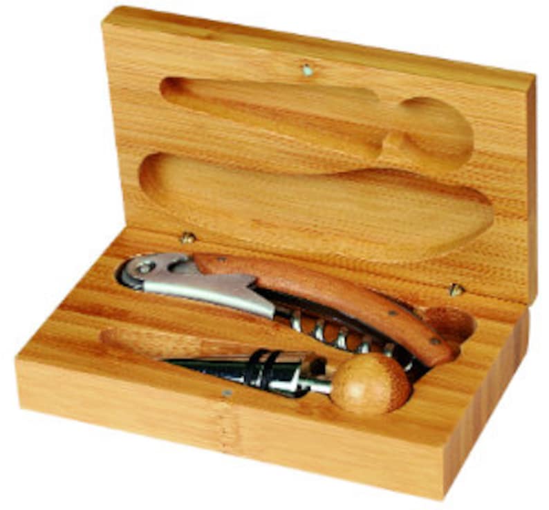 May include: A bamboo wine opener set in a wooden box. The set includes a corkscrew, a bottle stopper, and a foil cutter. The box is rectangular with a hinged lid and a natural wood finish. The corkscrew has a wooden handle and a stainless steel opener.