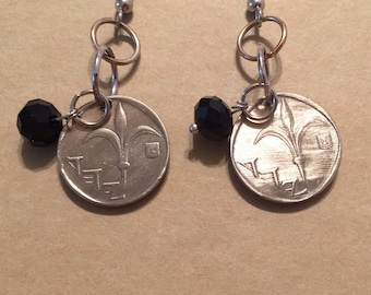 May include: A pair of silver earrings with black beads and coin charms. The coins feature a fleur-de-lis design and the text "1971" in French.