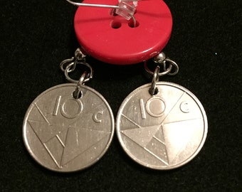 May include: A pair of silver earrings with a coin design featuring the text "10c" and a geometric pattern. The earrings are hanging from a red button.