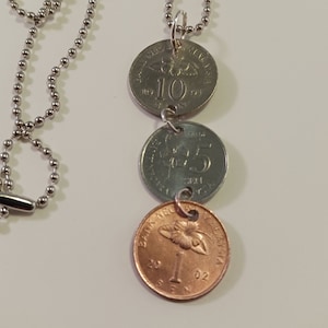 May include: A silver chain necklace with three silver coins attached. The coins are from Malaysia and feature the numbers "10", "25", and "1".