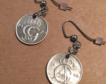 May include: A pair of silver earrings featuring vintage coins with the inscription "1979" and "1965" and a crown design.