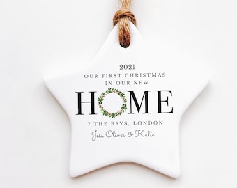 Peut inclure: Ornement de Noël blanc en forme d'étoile, avec une attache en corde de jute. L'ornement porte l'inscription "2021 Our First Christmas In Our New Home" et l'adresse "7 The Bays, London" ainsi que deux noms. Une couronne festive est au centre.
