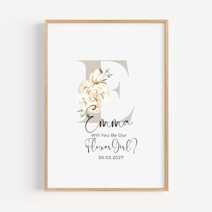 May include: A printable floral design with the letter E and the text "Emma Will You Be Our Flower Girl? 30.03.2027" in a light brown frame.