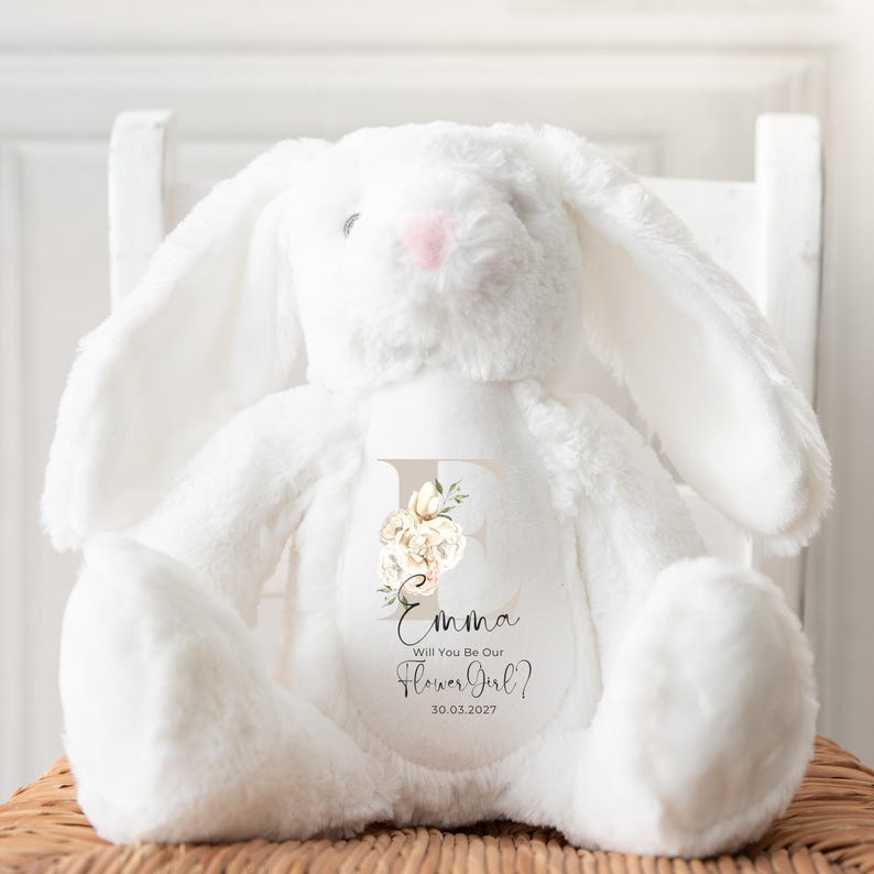 May include: White plush bunny with a floral letter E and the text "Emma Will You Be Our Flower Girl? 30.03.2027" on the chest.