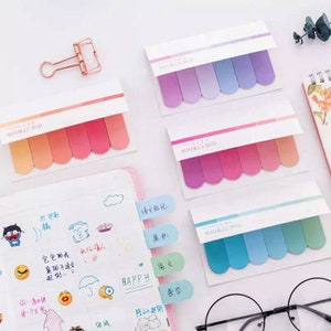May include: Four sets of colorful sticky notes with rounded edges. Each set has five notes in a gradient of pink, purple, blue, or orange. The notes are labeled "GUESTBOOK" in black text.