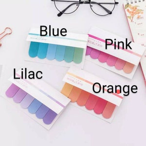May include: Four sets of colorful sticky notes with rounded edges. Each set has five notes in a gradient of blue, pink, lilac, and orange. The notes are labeled "Glue Stick Book" and the colors are labeled "Blue", "Pink", "Lilac", and "Orange".