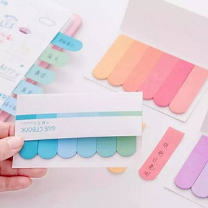 May include: A set of colorful sticky notes with rounded edges. The notes are in various shades of blue, pink, and purple. The notes are labeled "GUESTBOOK" and have the text "Happy Birthday" written on them.