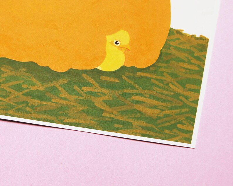 May include: A yellow bird with a closed eye is peeking out from under a large orange object. The bird is sitting on a bed of green and brown grass.