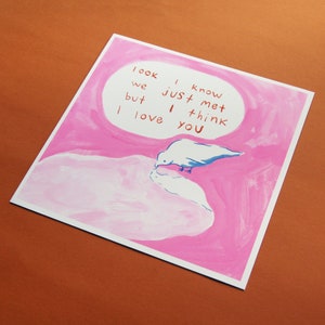 Pu&ograve; includere: Un'illustrazione ad acquerello rosa e bianca di un uccello che beve da una pozza d'acqua. L'illustrazione include il testo "look i know we just met but i think i love you".
