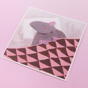 Pu&ograve; includere: Un'illustrazione ad acquerello di un topo grigio che dorme in un letto con un motivo rosa e marrone.