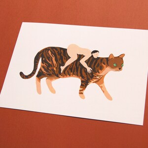 May include: A brown and black tabby cat with green eyes is walking with a person riding on its back. The person is nude and has brown hair.