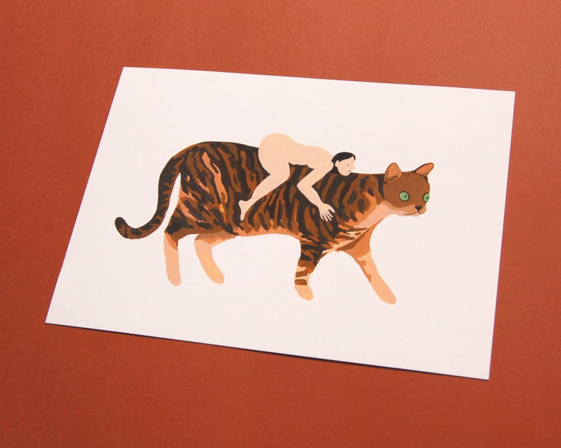 May include: A brown and black tabby cat with green eyes is walking with a person riding on its back. The person is nude and has brown hair.
