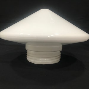 May include: A white, ceramic, mushroom-shaped object with a conical top and a wide, flat base. The base has a threaded design. The object is likely a decorative piece or a functional item, such as a lamp shade or a bottle stopper.