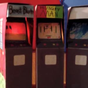 May include: Three cardboard arcade game cabinets with colorful designs. The cabinets are labeled "Beast Blaster", "Hungry Man", and "Space Invaders".
