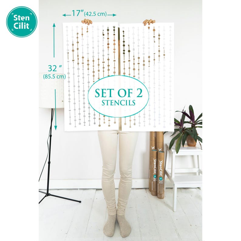 May include: A set of two stencils featuring a repeating pattern of small circles in shades of brown and gray. The stencils are 32 inches tall and 17 inches wide. The stencils are held by a person in front of a white wall. The text "SET OF 2 STENCILS" is printed on the stencils.