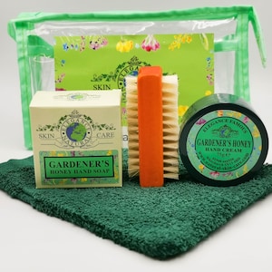 May include: A green wash bag with a floral print contains a set of hand care products: a bar of soap, a jar of hand cream, a brush, and a green towel. The products are labelled "Gardener's Honey" and "Elegance Natural Skin Care".