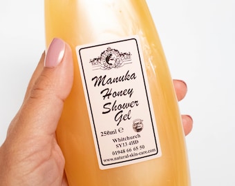 Könnte beinhalten: Eine durchsichtige Plastikflasche mit Manuka-Honig-Duschgel, mit einem weißen Etikett, auf dem "Manuka Honey Shower Gel", "250ml e", "Whitchurch SY13 4HD", "01948 66 65 50" und "www.natural-skin-care.com" steht.