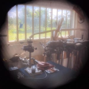 Puede incluir: Una vista cercana de un taller con varios motores fuera de borda vintage, un banco de trabajo y herramientas. Los motores están montados en soportes y están en diferentes estados de reparación. El banco de trabajo está cubierto de herramientas y piezas. El taller está iluminado por la luz natural que entra por una ventana.