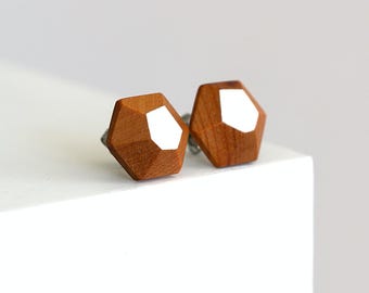 May include: A pair of geometric wooden earrings with white accents. The earrings are brown and have a hexagonal shape.