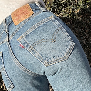 May include: A pair of blue denim jeans with a brown leather patch that reads "Levi Strauss & Co.  Quality Clothing" and "501  W 24 L 30".