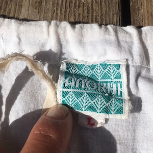 May include: A white drawstring bag with a green and white label that says "ANOKHI" and a size "L" tag.