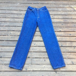 Puede incluir: Un par de pantalones vaqueros de mezclilla azul oscuro con un corte recto clásico.