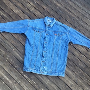 May include: A blue denim jacket with a button closure and two front pockets. The jacket has a faded look and is made of a soft, comfortable material.