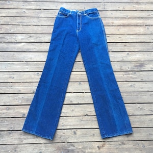 Puede incluir: Un par de pantalones vaqueros azules de pierna ancha y cintura alta.