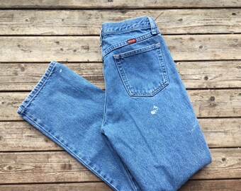 May include: A pair of light blue denim jeans with a brown leather patch on the back pocket. The jeans have a straight leg and a classic fit.