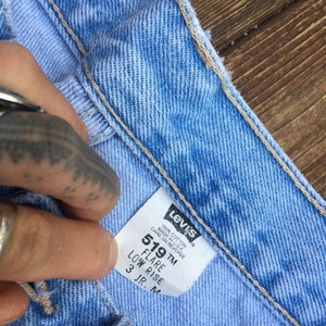 Puede incluir: Un primer plano de una etiqueta de mezclilla azul Levi's 519 flare de tiro bajo. La etiqueta es blanca con texto negro y dice "100% Algod&oacute;n Hecho en EE. UU. Cuidado en el reverso 519 TM Flare Tiro bajo 3 JR. M".