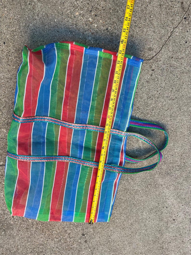 May include: A colorful striped tote bag with red, green, blue, and white vertical stripes. The bag has two handles and is approximately 26 inches long. The bag is made of a mesh-like material.