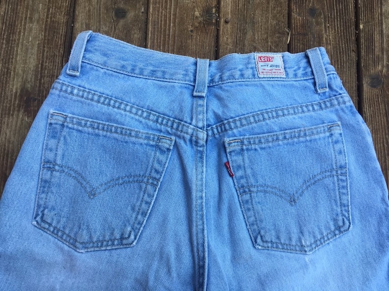 Puede incluir: Un par de pantalones vaqueros de mezclilla azul claro con bolsillos traseros y una etiqueta Levi's en la parte posterior de la cintura.