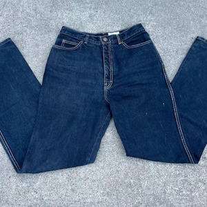 May include: A pair of dark blue denim jeans with a straight leg fit. The jeans have a button fly and belt loops.