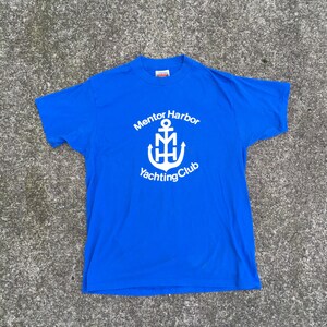May include: A royal blue t-shirt with a white anchor and the text "Mentor Harbor Yachting Club".