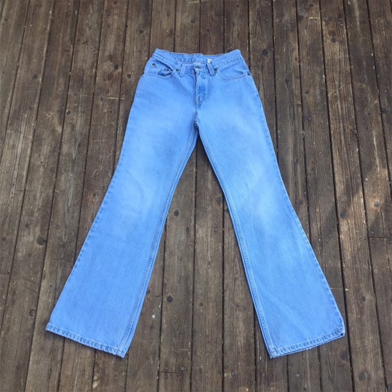 Puede incluir: Un par de pantalones vaqueros de mezclilla azul claro con pierna ancha, cintura alta y estilo cl&aacute;sico de cinco bolsillos.