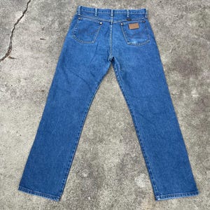 Puede incluir: Un par de pantalones vaqueros azules de mezclilla con un parche de cuero marr&oacute;n en el bolsillo trasero. Los pantalones tienen una pierna recta y un ajuste cl&aacute;sico.