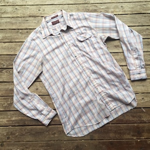 Pode incluir: Uma camisa de manga comprida xadrez com um padrão xadrez azul, branco e rosa. A camisa tem um colarinho abotoado e um único bolso no peito.