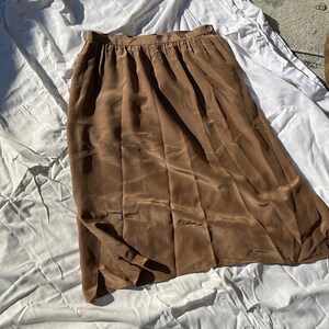 May include: A brown satin midi skirt with a straight silhouette and a simple waistband.