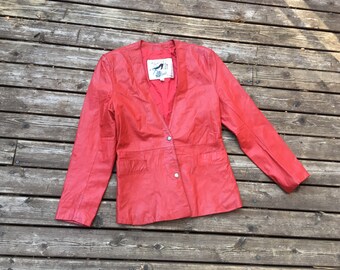 May include: A red leather jacket with a V-neck and a button fastening. The jacket has two pockets on the front and a label on the inside that says "S.O.S. by Susan O'Sullivan".