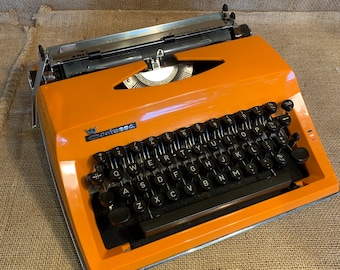 Vintage portable orange coloured Adler Contessa Deluxe typewriter in own carry case.