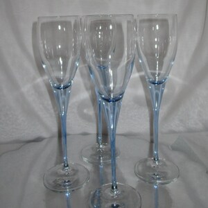 Puede incluir: Cuatro copas de champ&aacute;n transparentes con tallos y bases de color azul claro. Las copas tienen un dise&ntilde;o alto y delgado, ideal para celebraciones. Los tallos son de un azul delicado, a&ntilde;adiendo un toque de color a la elegante cristaler&iacute;a.