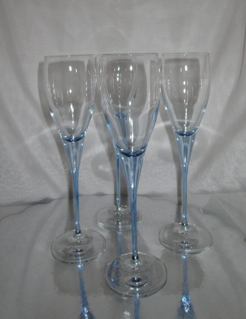 Puede incluir: Cuatro copas de champ&aacute;n transparentes con tallos y bases de color azul claro. Las copas tienen un dise&ntilde;o alto y delgado, ideal para celebraciones. Los tallos son de un azul delicado, a&ntilde;adiendo un toque de color a la elegante cristaler&iacute;a.