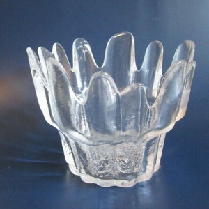 May include: A clear glass bowl with a unique, wavy, organic design. The bowl has a wide, open top and a narrow base.