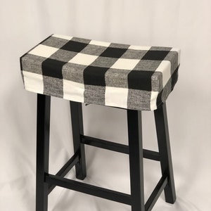 May include: Black and white buffalo plaid stool cover. The cover is made of a soft, woven fabric and fits over a standard bar stool.