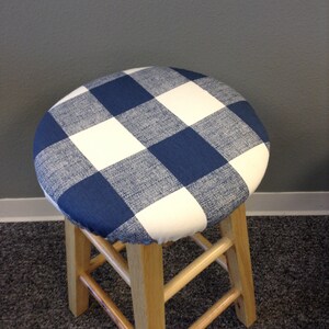 May include: A wooden stool with a blue and white checkered fabric seat cover.