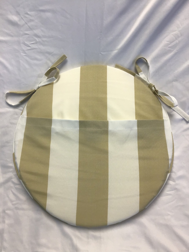 May include: Round chair cushion with a beige and white striped pattern. The cushion has ties on each side to secure it to a chair.