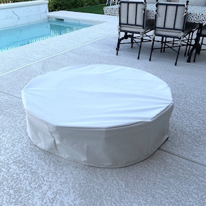 May include: White round patio table cover with a drawstring closure. The cover is made of a water-resistant material and is designed to protect your table from the elements.