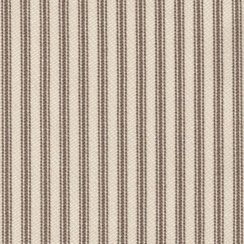 May include: A woven fabric featuring a repeating pattern of vertical stripes in a muted brown color against a light cream background. The texture of the textile is visible, showing a consistent weave throughout the entire surface of the material.