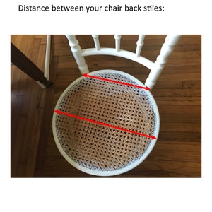 May include: White chair with a woven cane seat. The seat is marked with red lines to show the diameter of the seat.